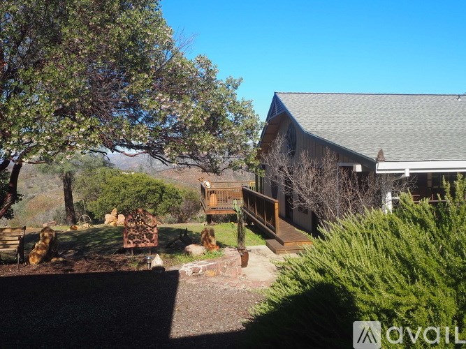 A house with a grey roof and a tree in front of it.