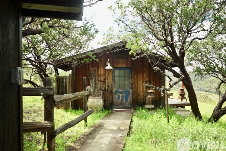A wooden building with a blue door and a porch.