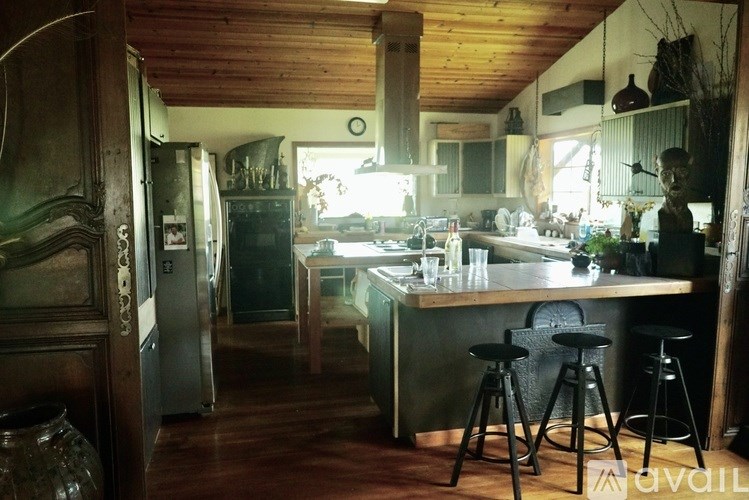 A kitchen with a wooden ceiling and a large island with stools.