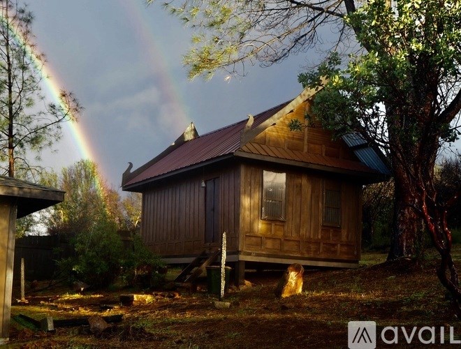 A wooden cabin with a rainbow in the background.