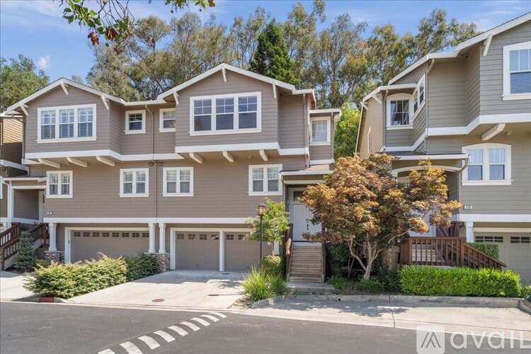 A row of houses with garages and trees in front.