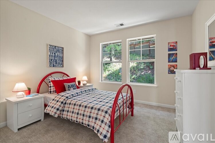 A bedroom with a bed, nightstand, and window.