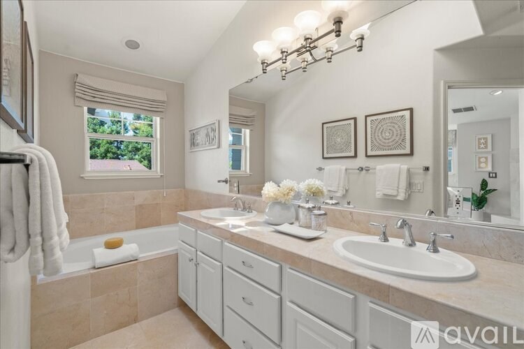 A bathroom with a large mirror, a white sink, and a bathtub with a towel on it.