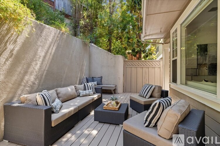 A patio with a couch, pillows, and a coffee table.