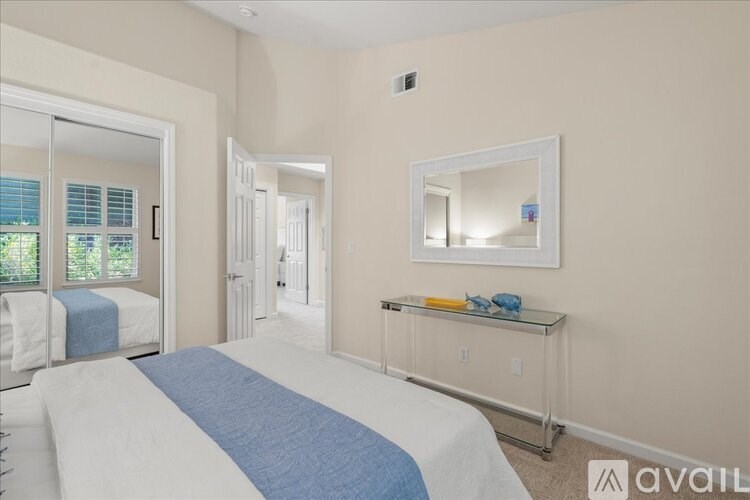 A bedroom with a bed, mirror, and a dresser with a blue cloth on it.