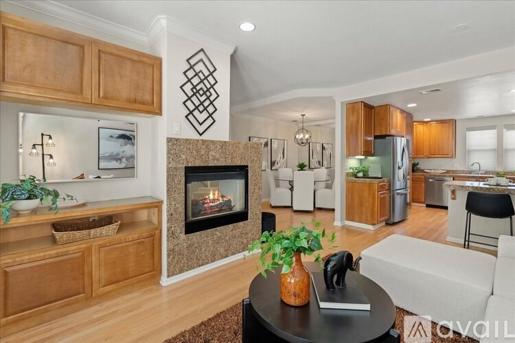 A modern living room with a fireplace and a dining area in the background.