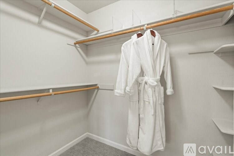 A white robe is hanging on a rack in a room.