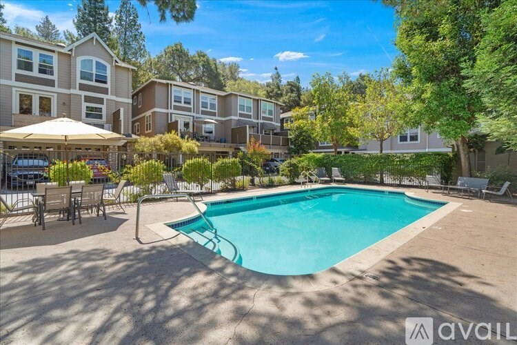 A swimming pool surrounded by a patio with chairs and umbrellas.