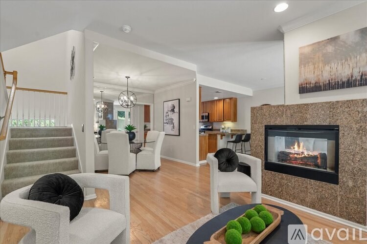 A living room with a fireplace and a dining area in the background.