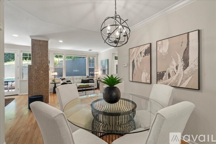 A modern dining room with a glass table and white chairs.