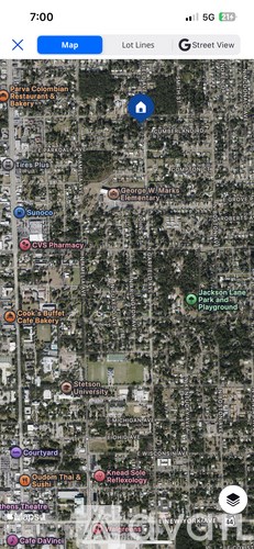 A map application is open on a phone screen showing a street view of a neighborhood with various points of interest marked.