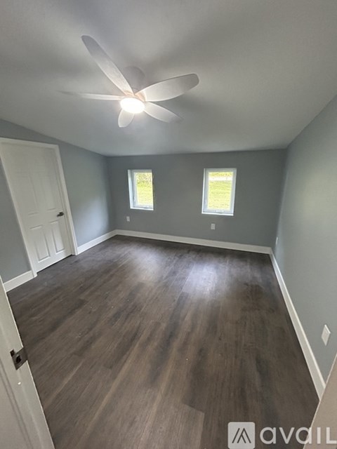 A room with a ceiling fan and wooden flooring.