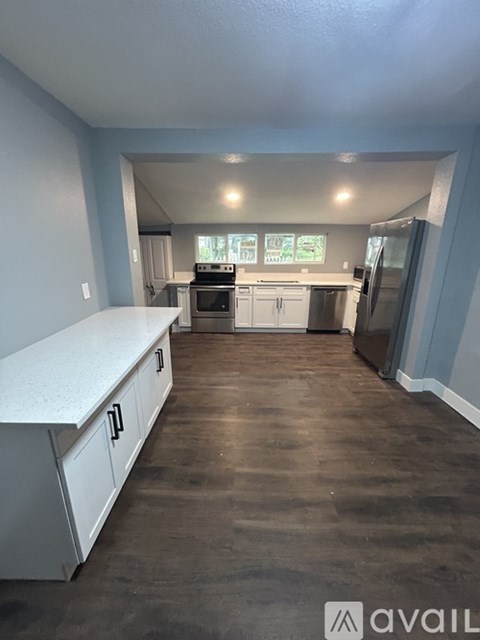 A kitchen with white cabinets and a countertop is available for rent.