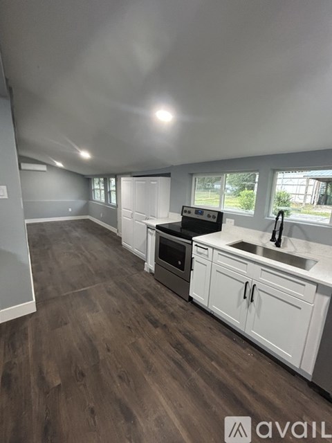A kitchen with white cabinets and a wooden floor.