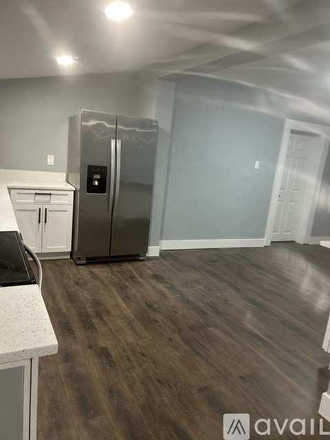 A kitchen with a refrigerator and wooden floors.