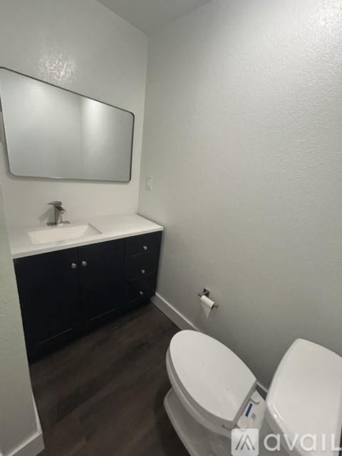 A bathroom with a toilet, sink, and mirror.