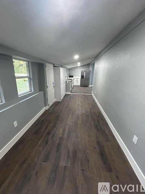 A long hallway with wood floors and white walls.