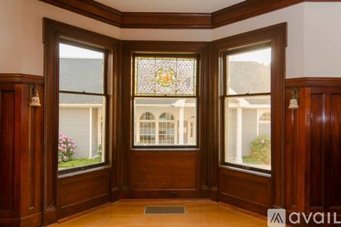 A room with a wooden floor and a large stained glass window.