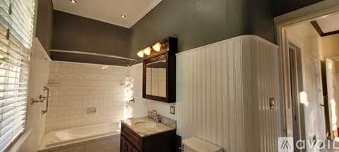 A bathroom with a white bathtub, sink, and a mirror.