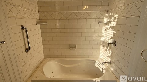A white tiled bathroom with a jacuzzi tub and a shower.