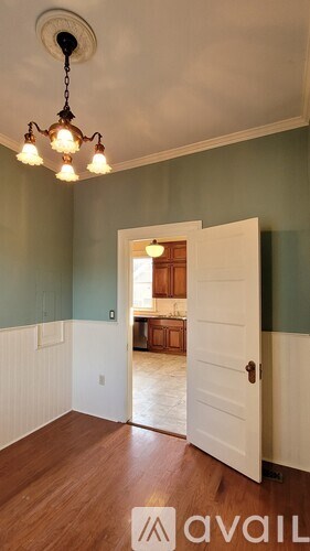 A room with a chandelier and a door leading to another room.