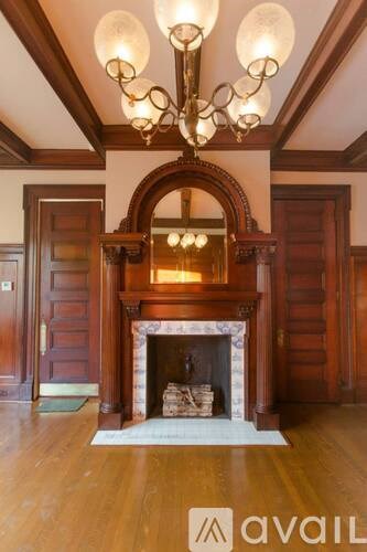 A large, ornate chandelier hangs over a fireplace in a room with wooden floors and walls.