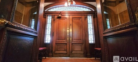A large wooden door with a glass window is flanked by two mirrors.