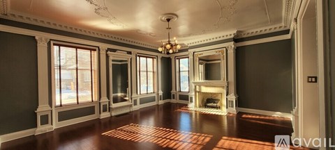 A large, empty room with wood floors and a fireplace.