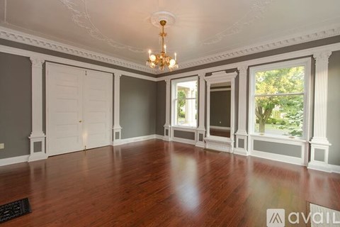 A large empty room with a chandelier and a door.