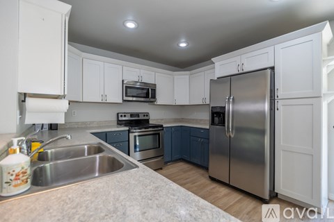 A kitchen with white cabinets and a stainless steel refrigerator.