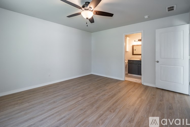 A room with a ceiling fan and a door leading to another room.
