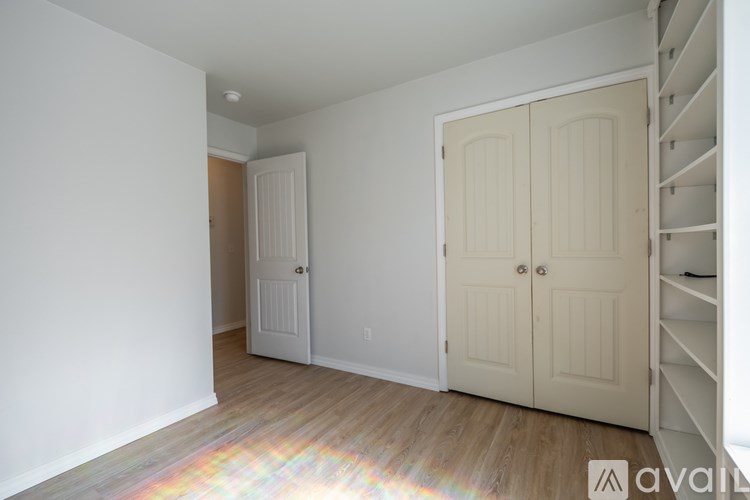 A room with a white door and a wooden floor.