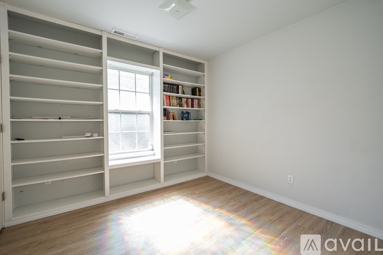 A room with a window and a bookshelf filled with books.