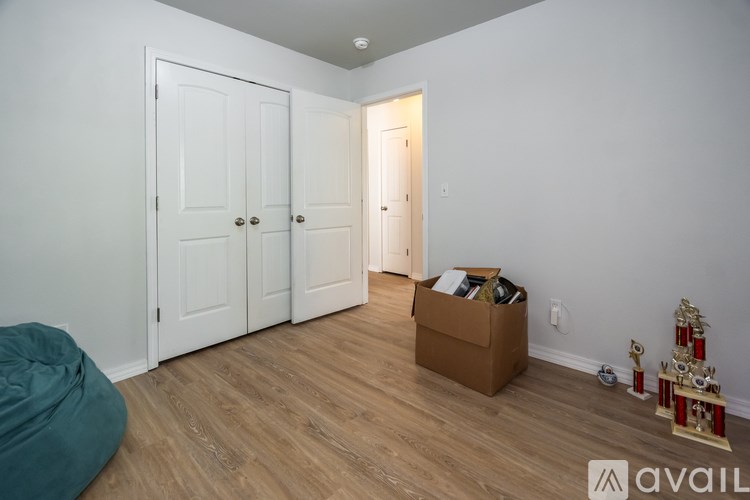 A room with a white door, a white wall, a brown box on the floor, and a green bean bag.