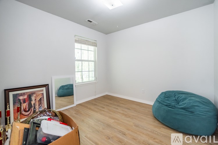 A room with a window, a bean bag chair, and a picture frame on the wall.
