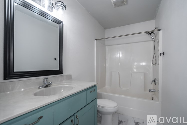 A bathroom with a white tub and a sink with a mirror above it.