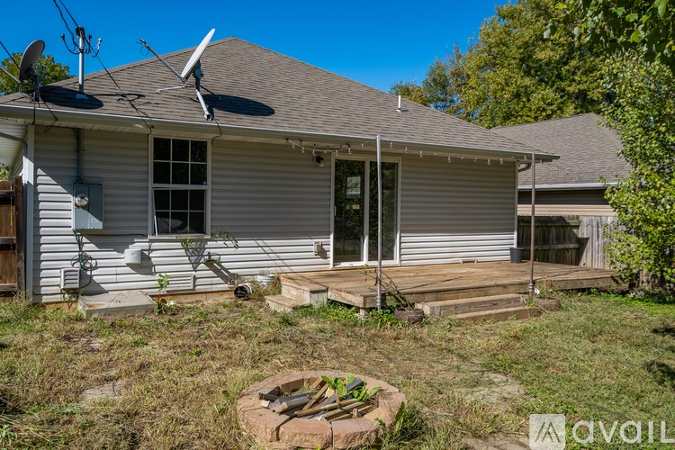 A house with a grey roof and a white door is surrounded by greenery.