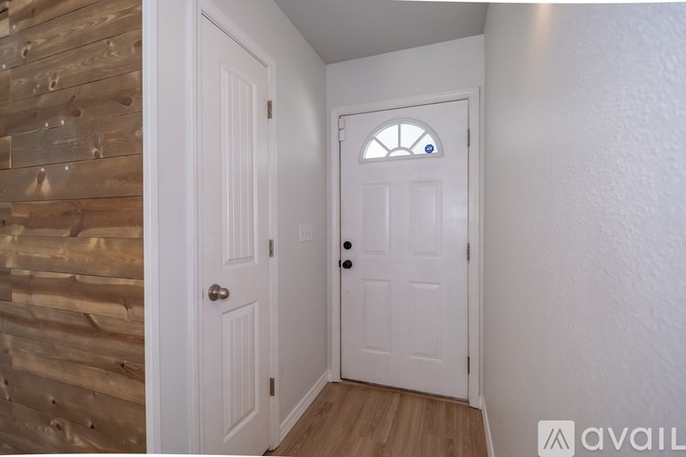 A white door with a round window is in a room with wooden walls.