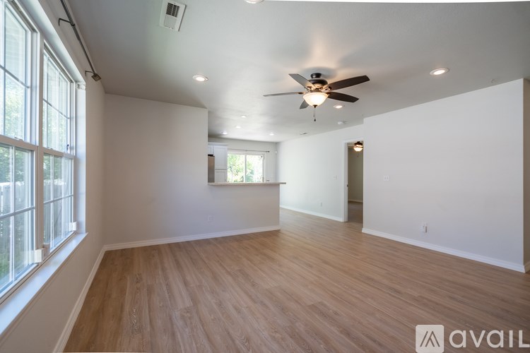 A spacious room with wooden flooring and a ceiling fan.