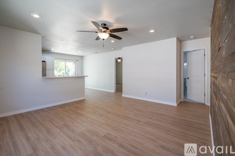 A spacious room with wooden flooring and a ceiling fan.