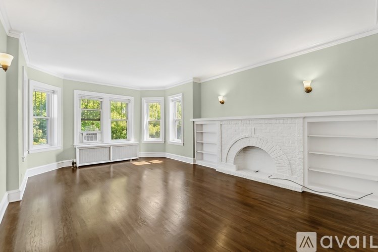 A spacious room with wood flooring and a fireplace.
