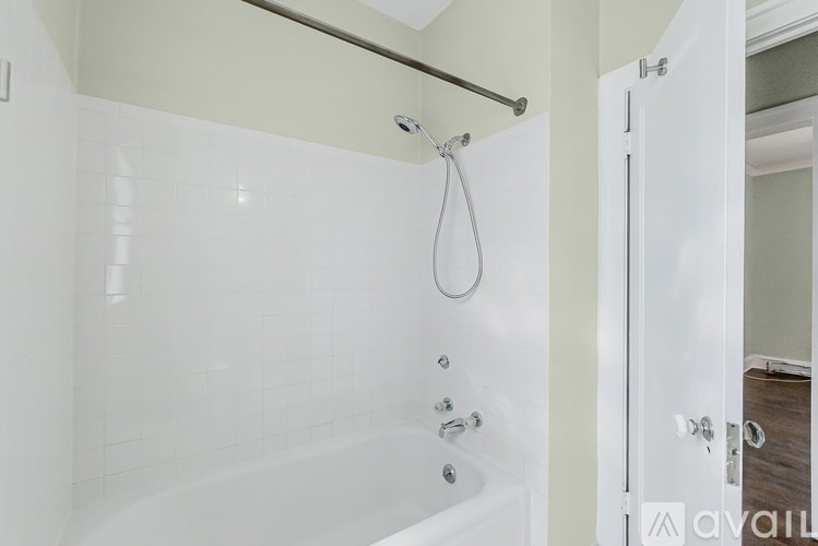 A white bathtub with a shower head and a door.