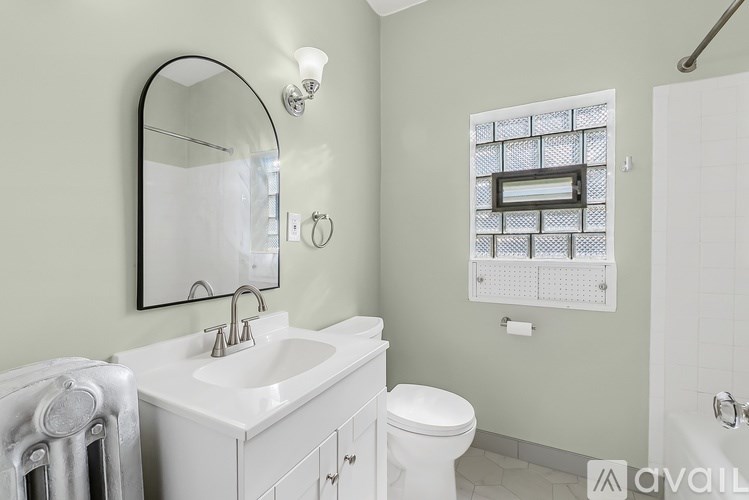 A bathroom with a white sink and toilet, a mirror, and a towel rack.