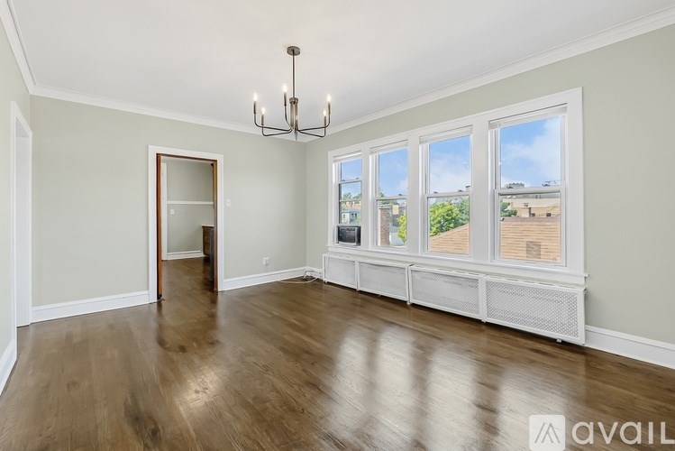 A room with a chandelier, hardwood floors, and a bay window with a view of the outdoors.
