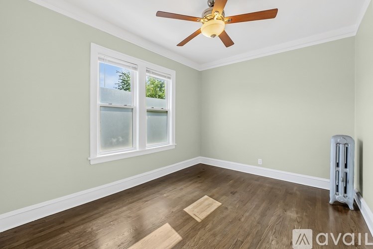 A room with a ceiling fan and a window with a view of trees.