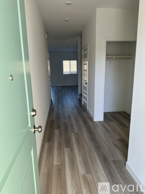 A long hallway with wood floors and white walls.