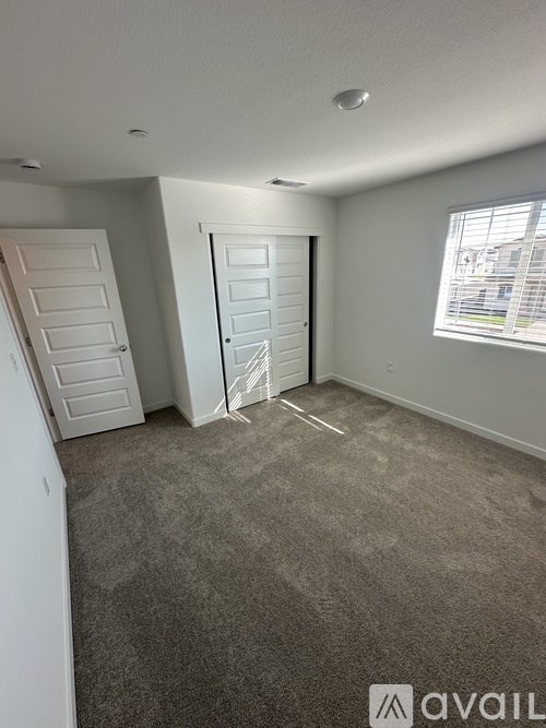 A room with a carpeted floor and a window with blinds.