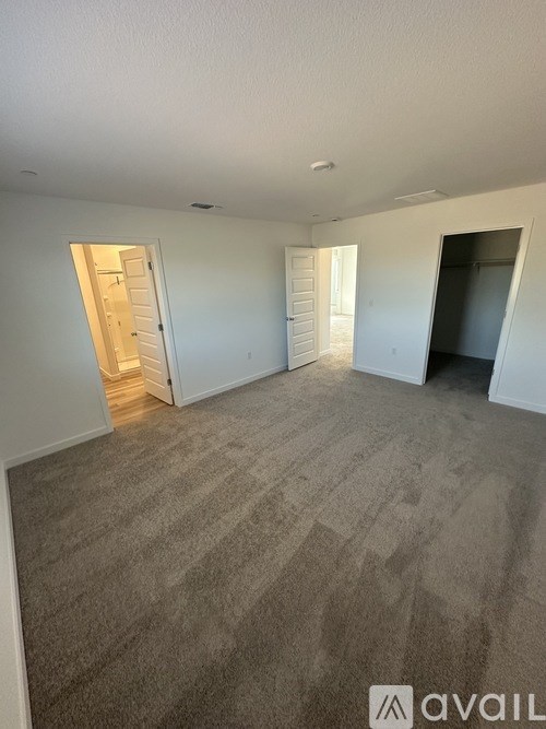 A carpeted room with two doors and one open.