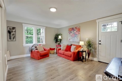 A living room with a red couch and a green plant.