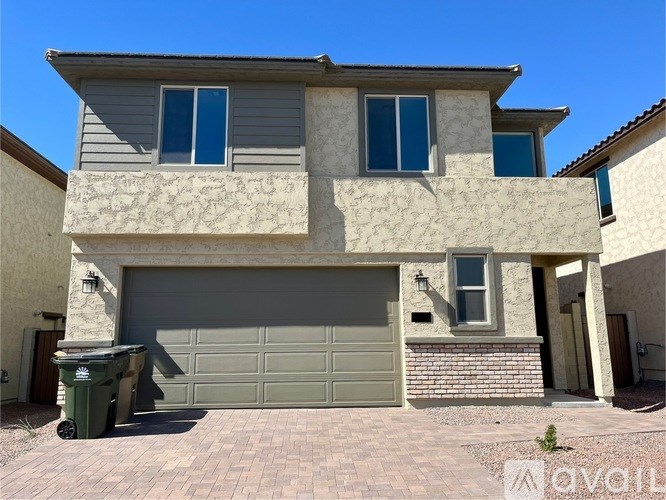A two-story house with a garage and a brick wall.